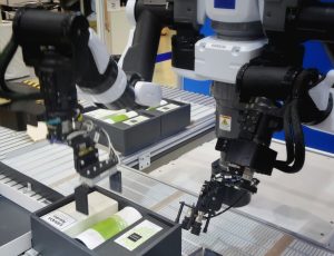 An image of robotic arms packaging products